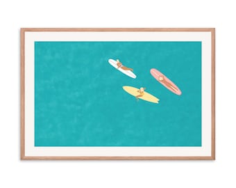 May include: Three people are lying on surfboards in a turquoise blue ocean. The surfboards are white, yellow, and pink.