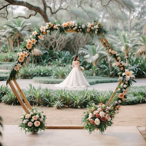 May include: A hexagonal wooden wedding arch decorated with peach and white flowers, greenery, and leaves. A bride in a white wedding dress walks towards the arch.