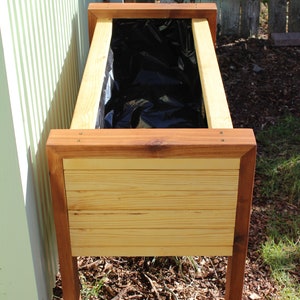 wood raised garden bed plans include how to line your planter with black plastic as shown in this image. It allows water to drain properly, without damaging the surrounding wood and compromising the strength of your newly built planter