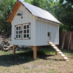 Right side view of the BnB chicken coop. Image shows the two front doors closed, with a chicken ramp going up the side chicken door on the chicken coop