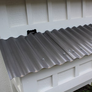 A close up of the chicken coop nesting box with a grey polycarbonate roof keeping the chickens dry