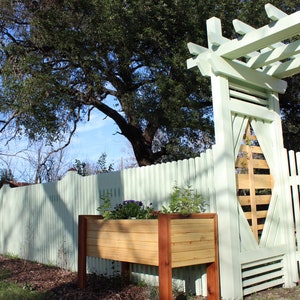 The modern planter, with horizontal pine slats, all the way around, are cornered by the redish brown hue of cedar. It shows that the plans for this garden bed can be a great accent to arbors