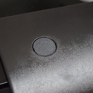 May include: Close-up of a black surface with two round, black, textured buttons.