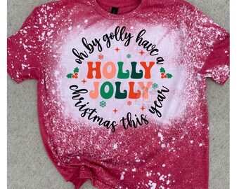 Peut inclure: T-shirt rouge avec un motif de blanchiment blanc. Le motif dit "Oh by golly have a Holly Jolly Christmas this year".