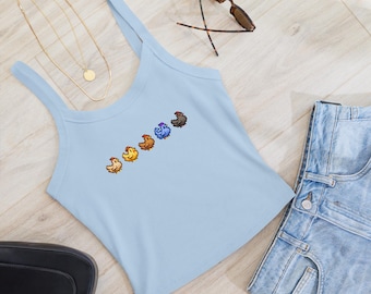 Può includere: Un top senza maniche di colore azzurro con un design a pixel di cinque galline in fila. Le galline sono di diversi colori, tra cui marrone, giallo, arancione, blu e nero.