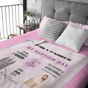 May include: Pink and white blanket with the text "Emily Parker My Baptism Day" and "The Church of Jesus Christ of Latter-day Saints". The blanket also features a picture of a temple, a heart with the text "Choose the Right", and a picture of Jesus Christ. The date "April 5th 2025" is also included.