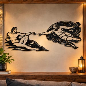 Può includere: Un'opera d'arte da parete in metallo nero che raffigura la Creazione di Adamo, con due figure che tendono le dita l'una verso l'altra. Il design è composto da due sagome separate con linee fluide e astratte che rappresentano le nuvole.