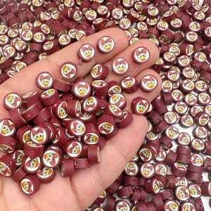 May include: A large pile of red and white round beads with a cartoon chick design. The beads are small and have a hole in the center for stringing.
