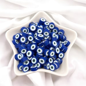 May include: A white ceramic star-shaped bowl filled with blue and white evil eye beads. The beads are round and have a white eye with a blue pupil in the center.