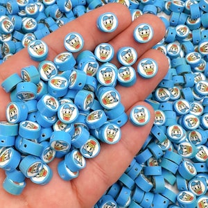 May include: A large pile of blue and white plastic beads with a cartoon duck face on each bead. The beads are small and round, and they are perfect for making jewelry or other crafts.