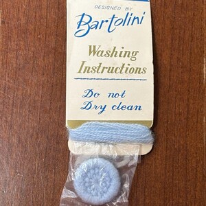 May include: Vintage Bartolini washing instructions card with a blue and white design. The card reads "Washing Instructions" and "Do not Dry clean". A small blue yarn sample and a blue knitted item are attached.