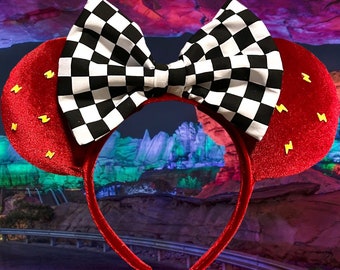 May include: Red mouse ears with a black and white checkered bow and yellow lightning bolt accents.