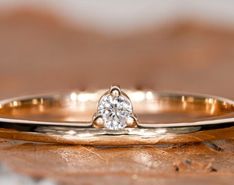 May include: A simple gold band ring with a single, small, round diamond set in the center.