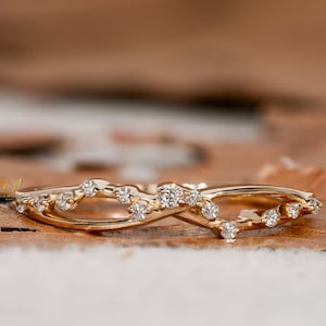 May include: A delicate gold band ring with a delicate, intertwined design featuring small diamonds.