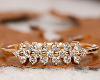 May include: A delicate gold band ring with a row of five flower-shaped clusters of small diamonds.