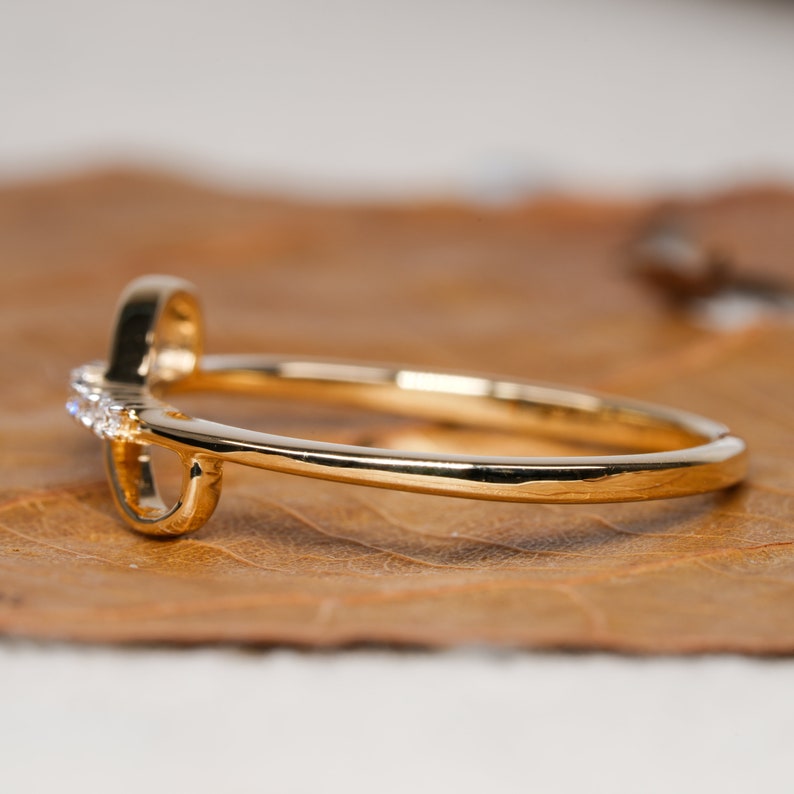 K&ouml;nnte beinhalten: Ein goldener Ring mit einem zarten Herzdesign und kleinen, klaren Steinen, die entlang des Bandes gesetzt sind.