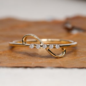 May include: A gold infinity ring with five small diamonds set in the band.