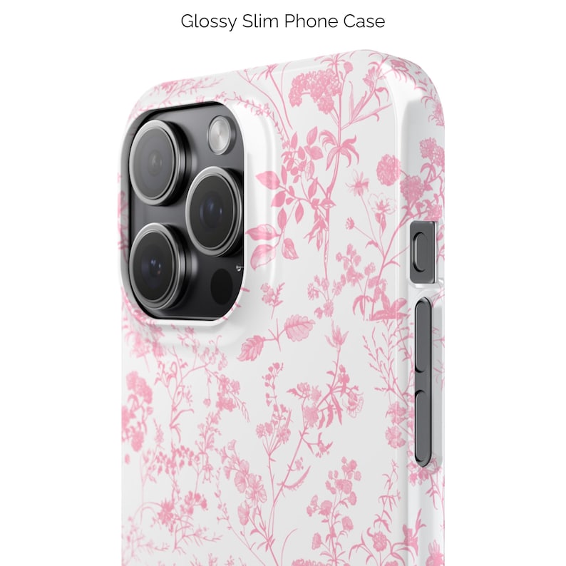 Pode incluir: Uma capa de telefone branca com um padr&atilde;o floral rosa. A capa tem um acabamento brilhante e um recorte para a lente da c&acirc;mera.