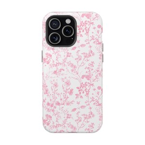 Pode incluir: Uma capa de telefone branca com um padr&atilde;o floral rosa. A capa tem um recorte para a lente da c&acirc;mera.