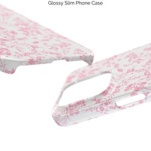 Pode incluir: Uma capa de telefone branca com um padr&atilde;o floral rosa. A capa &eacute; brilhante e fina.