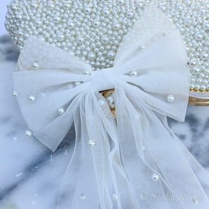 White Pearl Bow Veil for Bride. Enhance the allure of pre-wedding celebrations with the 2024 Trendy Bow Veil – a sophisticated bridal hairpiece designed for the bride-to-be, making it an exquisite bridal shower gift.