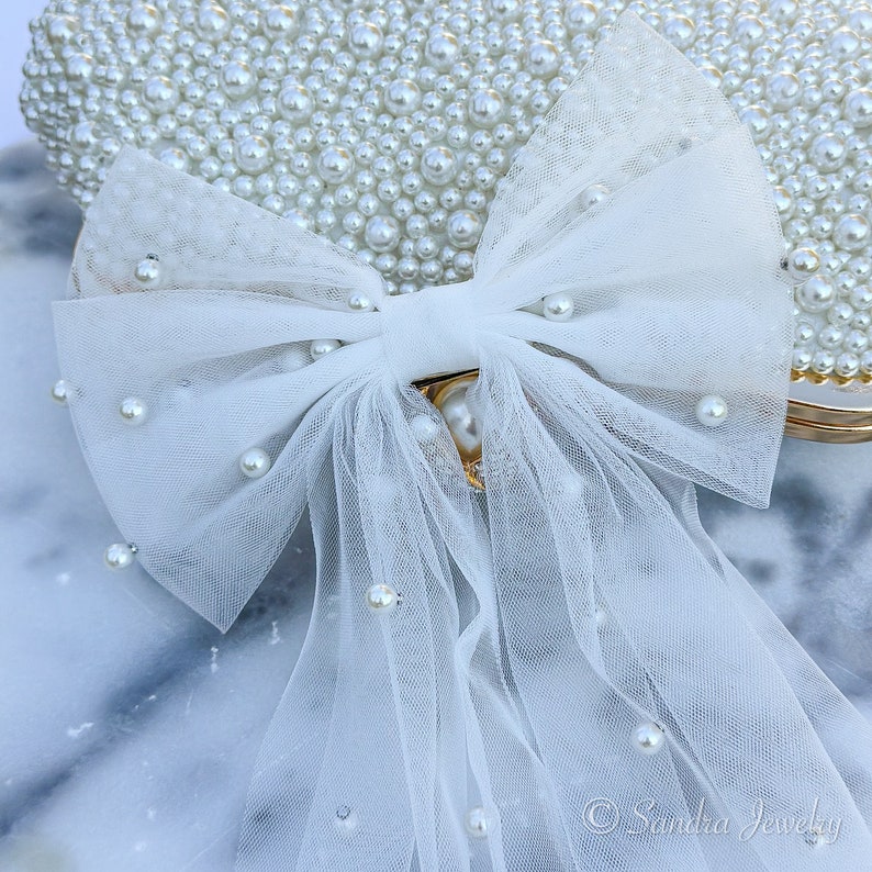 White Pearl Bow Veil for Bride. Enhance the allure of pre-wedding celebrations with the 2024 Trendy Bow Veil – a sophisticated bridal hairpiece designed for the bride-to-be, making it an exquisite bridal shower gift.