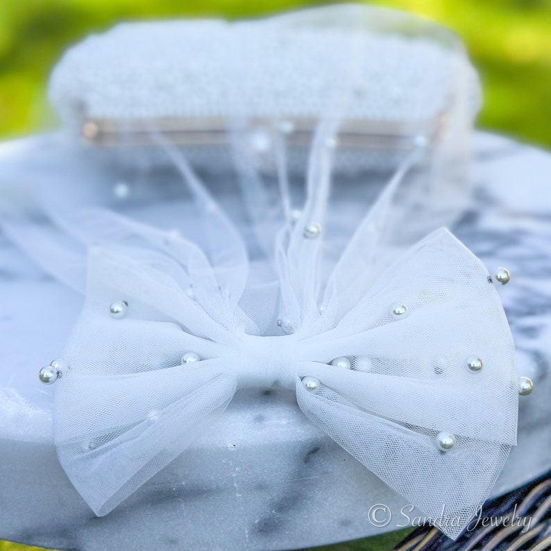 Small Pearl Tulle Bow Clip for Bride. Dazzle the bachelor party with the 2024 Trendy Bow Veil – a chic bridal hairpiece adorned with pearls, making it an ideal gift for bridal showers and a must-have for the bride-to-be.