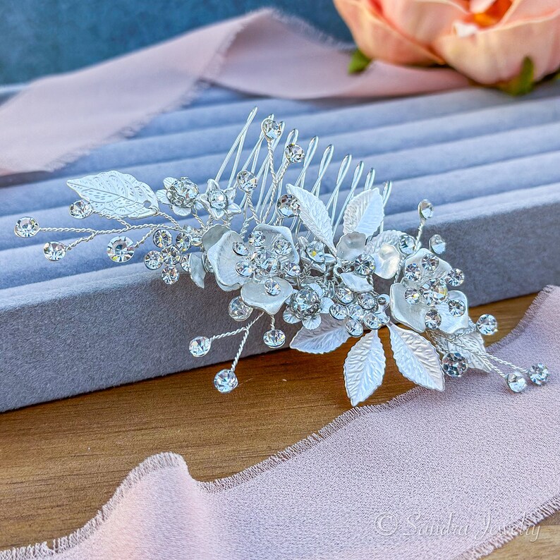 Elegant silver finish hair accessory adorned with lustrous flowers and leaves - the perfect complement for a graceful and refined hairstyle.