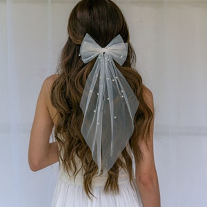 White Pearl Veil-Bow for Wedding day. Elevate your style with the enchanting pearl bow barrette – a meticulously crafted hairpiece that effortlessly complements various occasions, from bachelorette festivities to casual date nights.