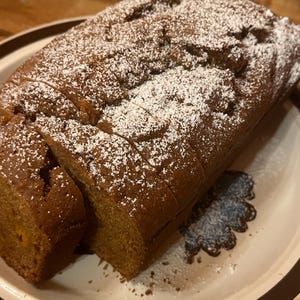 May include: A loaf of pumpkin bread dusted with powdered sugar, sliced and ready to eat.