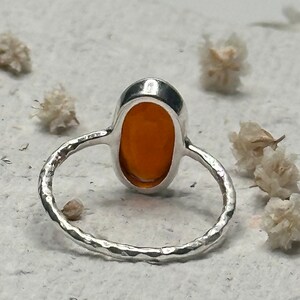 Peut inclure: Une bague en argent avec une bande martel&eacute;e et une pierre pr&eacute;cieuse orange de forme ovale.