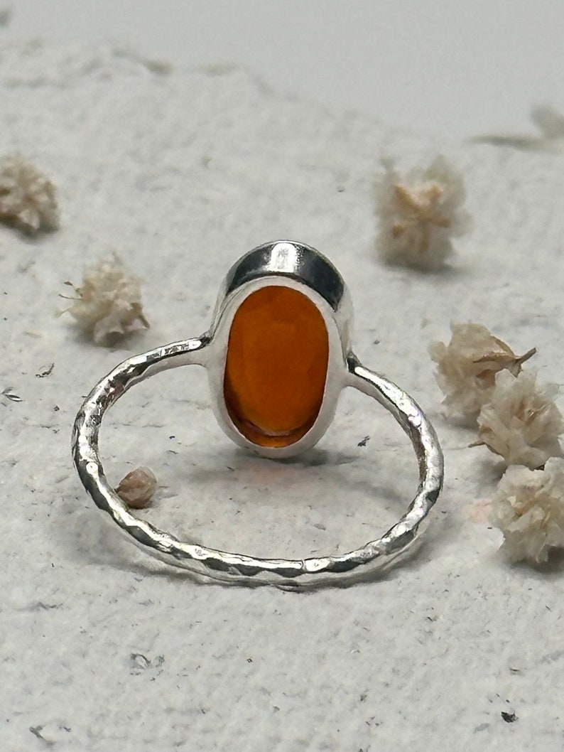 Peut inclure: Une bague en argent avec une bande martel&eacute;e et une pierre pr&eacute;cieuse orange de forme ovale.