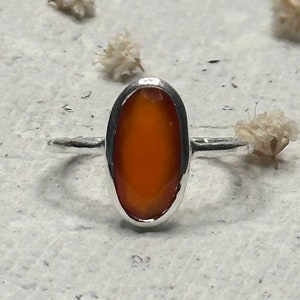 Peut inclure: Une bague en argent avec une pierre pr&eacute;cieuse orange de forme ovale sertie dans une monture &agrave; sertir.