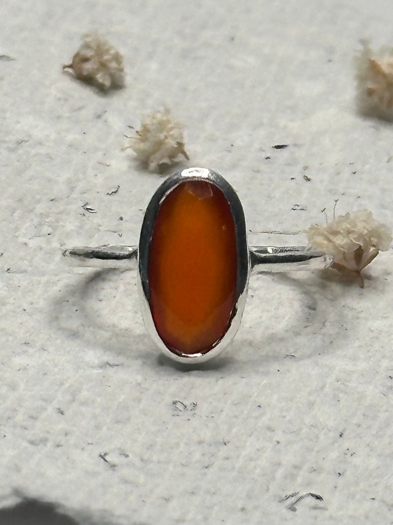 Peut inclure: Une bague en argent avec une pierre pr&eacute;cieuse orange de forme ovale sertie dans une monture &agrave; sertir.
