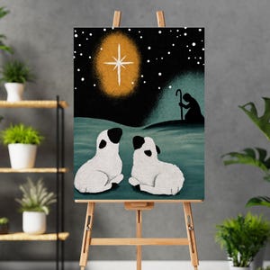 May include: A vertical art print featuring a dark night sky with a bright yellow star and white dots. Below, two white sheep with black ears and faces rest on a teal landscape. A dark silhouette of a person holding a staff stands in the distance.