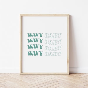 Puede incluir: Una impresión enmarcada con el texto "Wavy Baby" repetido cuatro veces en un color azul verdoso. El texto está en un estilo de fuente ondulado.