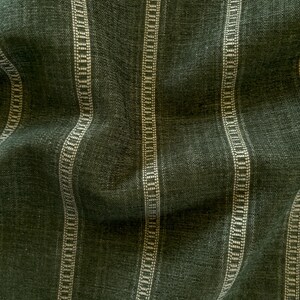 Puede incluir: Primer plano de una tela verde oscuro con rayas verticales. Las rayas alternan entre verde oscuro liso y un patr&oacute;n punteado de color crema. La tela tiene un aspecto texturizado, con hilos tejidos visibles.