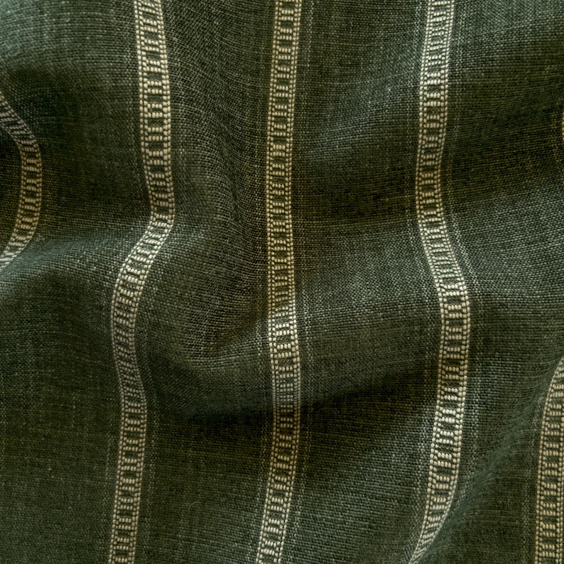 Puede incluir: Primer plano de una tela verde oscuro con rayas verticales. Las rayas alternan entre verde oscuro liso y un patr&oacute;n punteado de color crema. La tela tiene un aspecto texturizado, con hilos tejidos visibles.