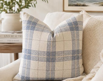 Peut inclure: Un coussin carré en tissu beige aspect lin avec un motif à carreaux bleu et beige. Le design se compose de lignes verticales et horizontales qui s'entrecroisent pour former une grille sur la surface de la housse de coussin.
