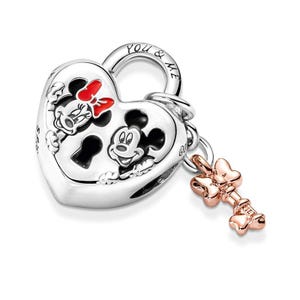 May include: Silver charm in the shape of a heart lock with Mickey and Minnie Mouse on it. The lock has the words "You & Me" engraved on it. A small key charm with a bow is attached to the lock.