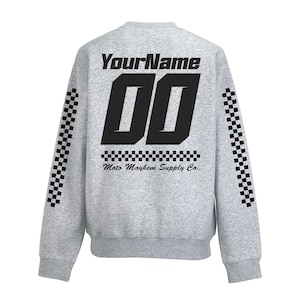 Peut inclure: Sweat-shirt gris avec des manches à carreaux noirs et un motif noir au dos. Le motif dit "YourName 00 Moto Mayhem Supply Co."