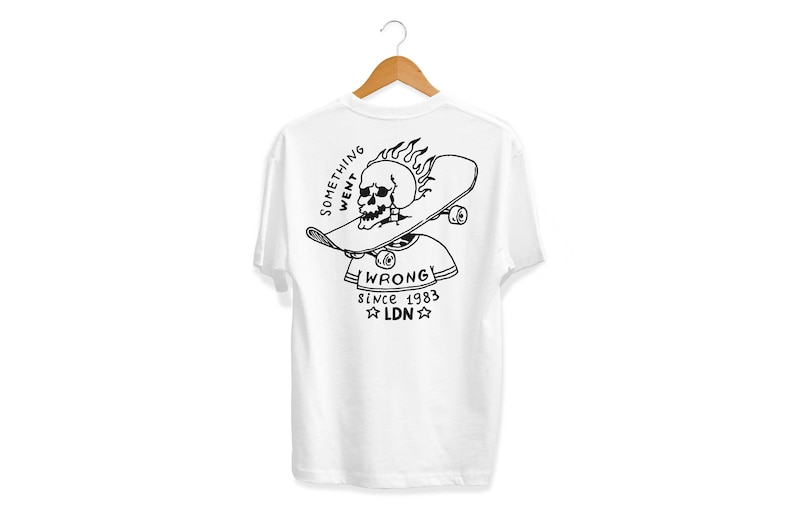K&ouml;nnte beinhalten: Wei&szlig;es T-Shirt mit einem schwarz-wei&szlig;en Grafikdruck eines Sch&auml;dels auf einem Skateboard mit Flammen. Der Text "SOMETHING WENT WRONG! since 1983 LDN" ist unter dem Grafikdruck aufgedruckt.