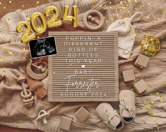 May include: A letter board with the text "Poppin' a different kind of bottles this year. Baby Forrester August 2024."  The board is surrounded by gold balloons spelling out "2024", a baby hat, wooden toys, and gold confetti.