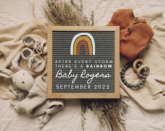 May include: A gray letter board with a rainbow graphic and the text "After every storm there's a rainbow Baby Rogers September 2022". The board is surrounded by baby items, including a pair of shoes, a stuffed bunny, a knitted onesie, and a wooden teething ring.