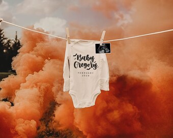 May include: A white baby onesie with long sleeves hangs on a clothesline with a wooden clothespin. The onesie has the words "Baby Gregory February 2024" printed on it in black script. An ultrasound image is clipped to the line. Orange smoke fills the background.