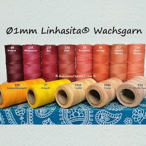 Könnte beinhalten: Eine Sammlung von 11 Spulen mit 1 mm gewachstem Garn in verschiedenen Farben, darunter Rot, Orange, Gelb und Beige. Die Spulen sind mit Nummern und deutschen Namen für die Farben beschriftet.