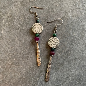 Könnte beinhalten: Silberne Ohrringe mit grünen und rosa Perlen und einem silbernen Anhänger mit geometrischem Muster.