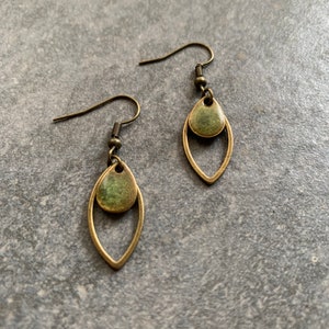 Könnte beinhalten: Ein Paar bronzefarbene Ohrringe mit einem grünen tropfenförmigen Anhänger. Die Ohrringe haben ein schlichtes, elegantes Design.