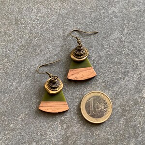 May include: A pair of green and brown wood earrings with gold accents. The earrings are shaped like a triangle with a rounded bottom.