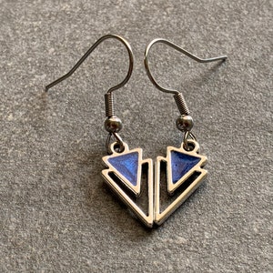 Könnte beinhalten: Ein Paar silberne Ohrringe mit einem geometrischen Design mit blauen Emailletriangeln.
